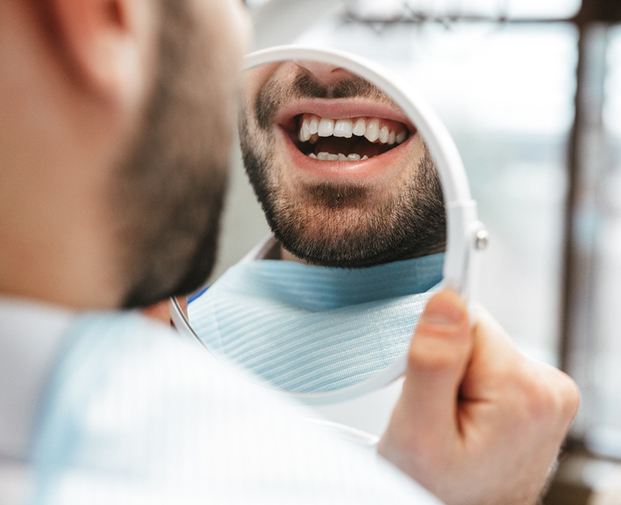 Man’s teeth reflected in handheld mirror
