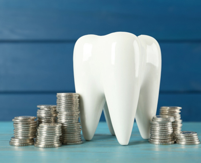 A ceramic tooth model surrounded by stacks of coins 