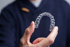 Dentist holding up an Invisalign clear aligner