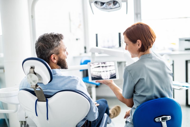 A middle-aged man talking to his dentist during a dental checkup