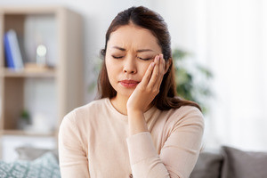 Woman sitting on couch with tooth pain