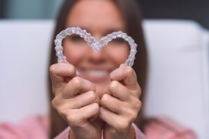 Dental staff making heart shape with clear aligners.