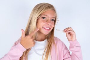 Teen smiling while holding her Invisalign tray